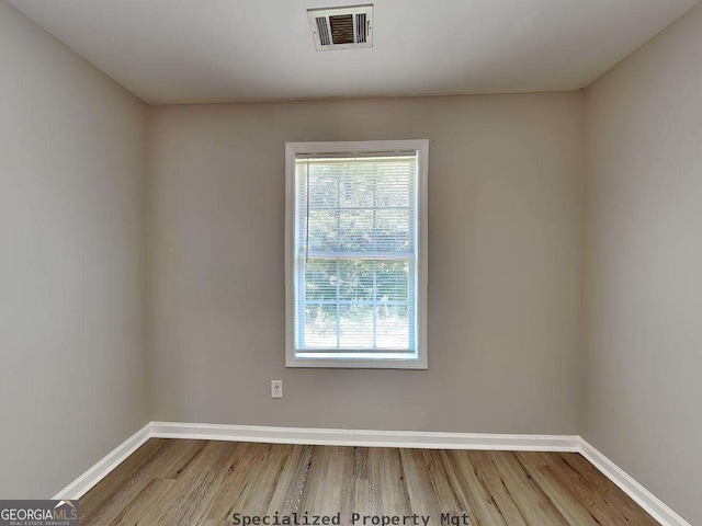 unfurnished room with visible vents, baseboards, and wood finished floors