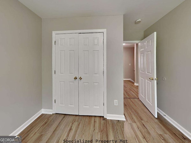 unfurnished bedroom featuring a closet, wood finished floors, and baseboards