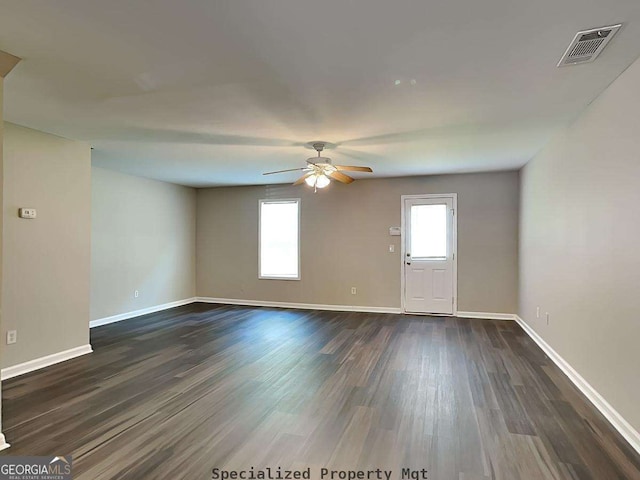 unfurnished living room with dark wood-style floors, a ceiling fan, visible vents, and baseboards