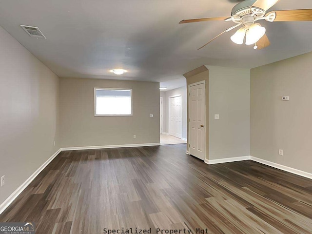 unfurnished room featuring dark wood-style flooring, visible vents, and baseboards