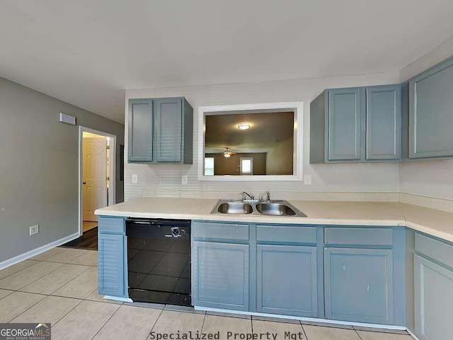 kitchen with light tile patterned floors, black dishwasher, light countertops, blue cabinetry, and a sink