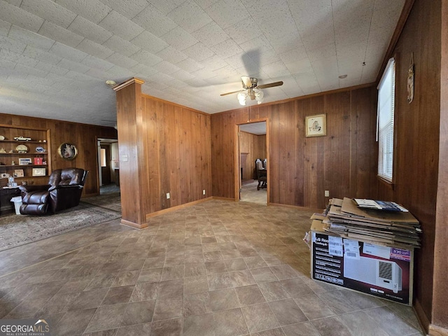 interior space featuring built in shelves, wooden walls, and a ceiling fan