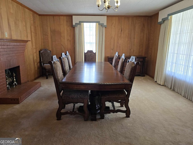 dining space with light carpet, an inviting chandelier, a fireplace, and ornamental molding