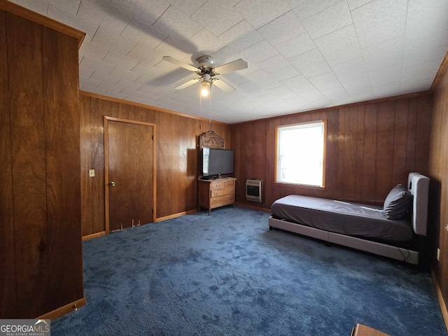 bedroom with carpet floors, wooden walls, a ceiling fan, and heating unit