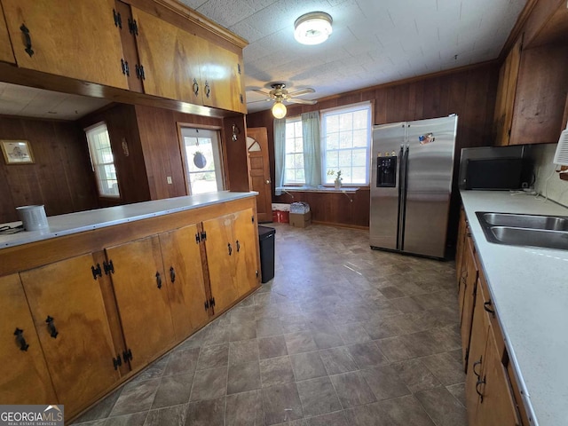 kitchen with wooden walls, black microwave, and stainless steel refrigerator with ice dispenser