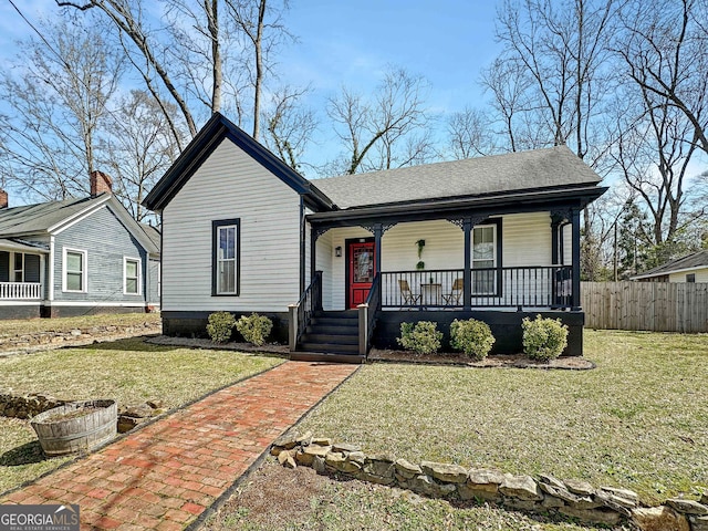 view of front of property featuring a porch, fence, and a front lawn