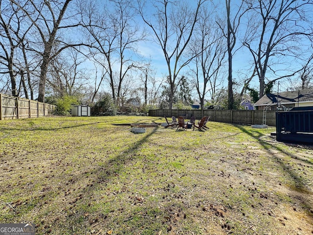 view of yard with an outbuilding, a storage unit, a fire pit, and a fenced backyard