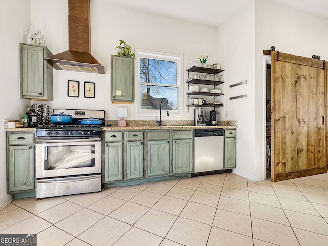 kitchen featuring a barn door, wall chimney range hood, dishwasher, gas stove, and green cabinetry