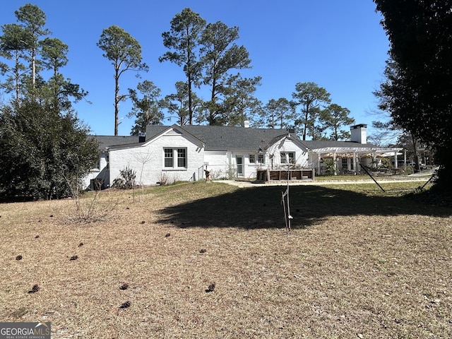 rear view of property with a yard and a pergola