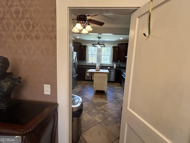 kitchen featuring a kitchen island, ceiling fan, dark brown cabinetry, appliances with stainless steel finishes, and crown molding