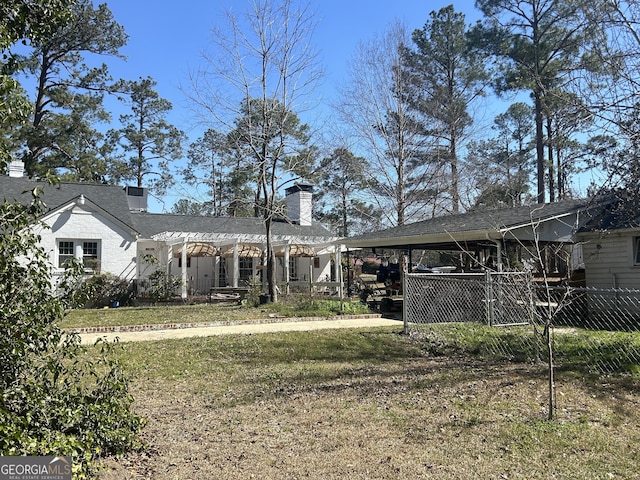 back of property with an attached carport, a yard, and fence