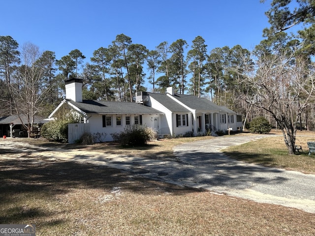 ranch-style house with a chimney and gravel driveway