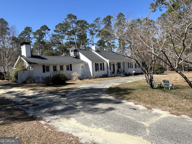 view of front facade featuring gravel driveway, central AC, and a chimney