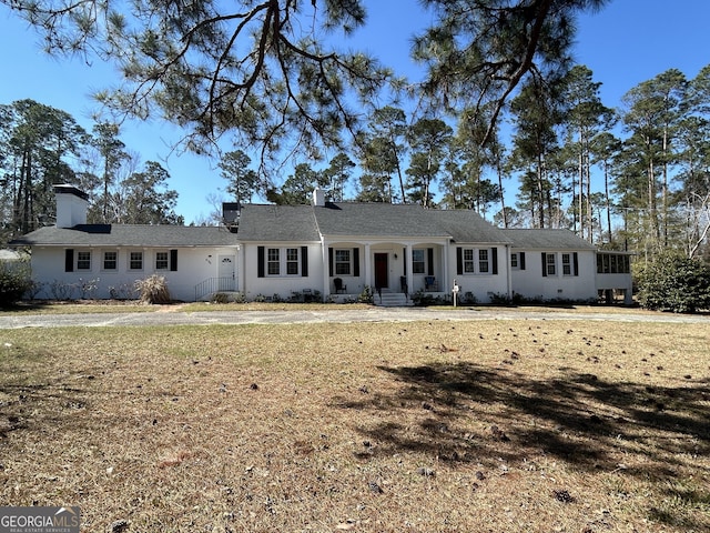 ranch-style house with a chimney and a front yard