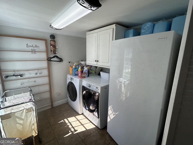 clothes washing area with cabinet space, dark tile patterned flooring, separate washer and dryer, and baseboards