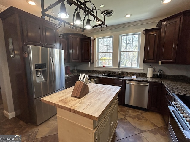 kitchen featuring visible vents, butcher block countertops, a sink, dark brown cabinets, and appliances with stainless steel finishes