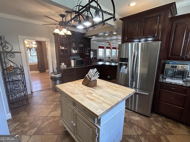 kitchen featuring ornamental molding, dark brown cabinetry, appliances with stainless steel finishes, wood counters, and a center island