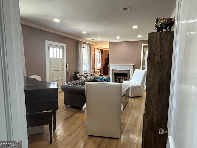 living room featuring light wood-style flooring, recessed lighting, a high end fireplace, and ornamental molding