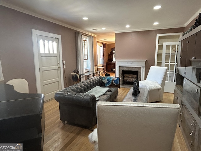 living room featuring recessed lighting, light wood-style flooring, a fireplace, and ornamental molding