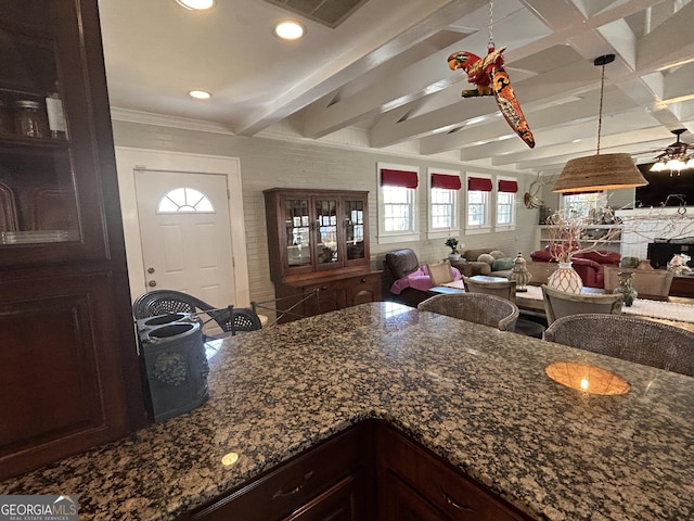 kitchen with dark stone countertops, visible vents, beam ceiling, dark brown cabinets, and open floor plan