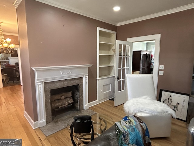 living area featuring ornamental molding, wood finished floors, a high end fireplace, an inviting chandelier, and baseboards