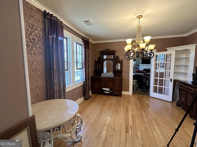 dining space featuring light wood-type flooring, visible vents, crown molding, wallpapered walls, and a chandelier