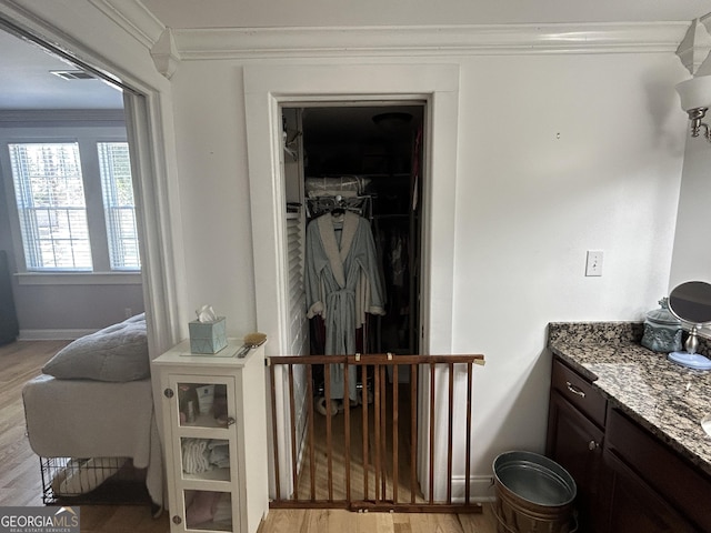 bathroom featuring visible vents, wood finished floors, crown molding, baseboards, and vanity