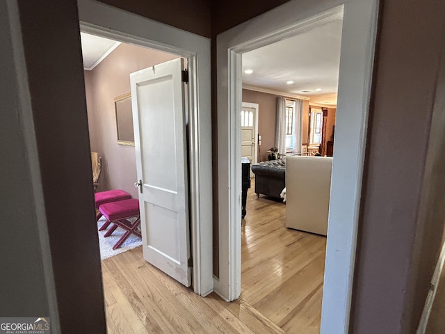 hallway with crown molding and light wood-type flooring