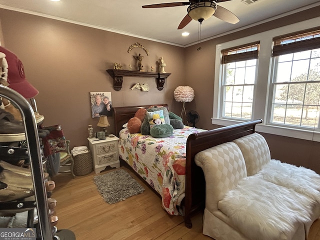 bedroom with crown molding, a ceiling fan, and wood finished floors