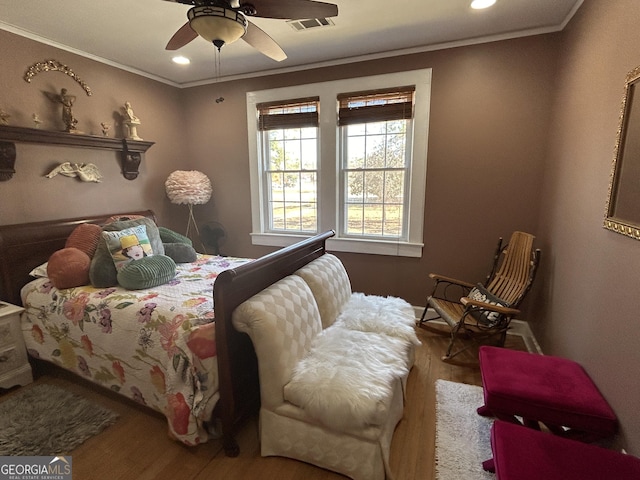 bedroom featuring visible vents, a ceiling fan, wood finished floors, and crown molding