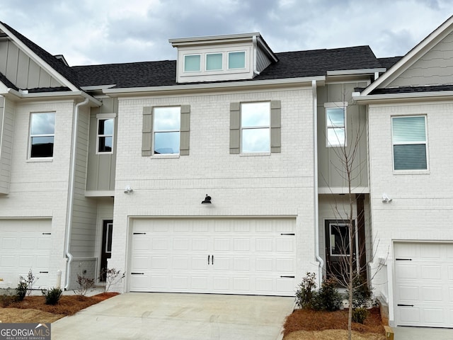 townhome / multi-family property featuring concrete driveway, brick siding, an attached garage, and roof with shingles