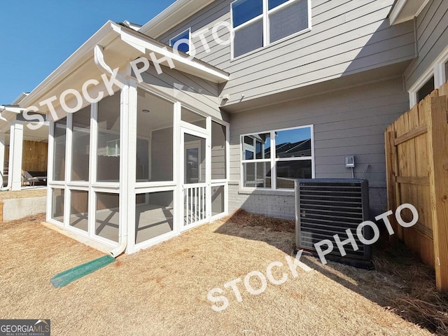 view of home's exterior featuring a sunroom, fence, and central AC