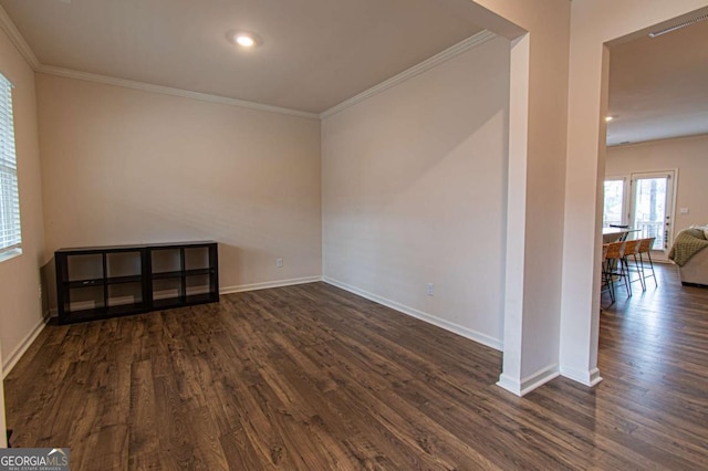 empty room featuring ornamental molding, dark wood-type flooring, and baseboards