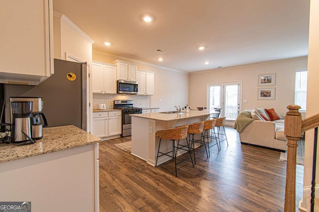 kitchen featuring a sink, white cabinetry, a kitchen breakfast bar, appliances with stainless steel finishes, and tasteful backsplash