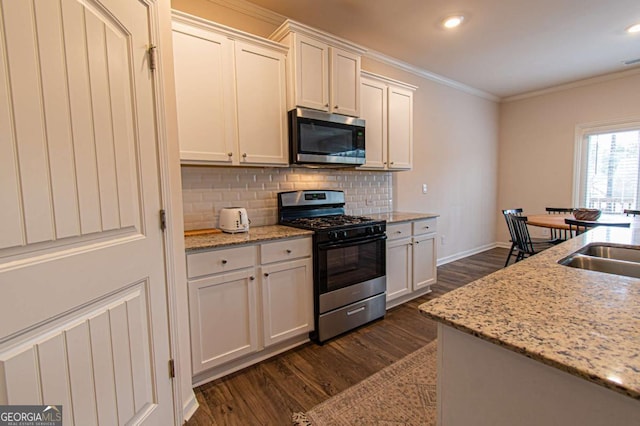 kitchen featuring stainless steel microwave, dark wood finished floors, gas range, and crown molding