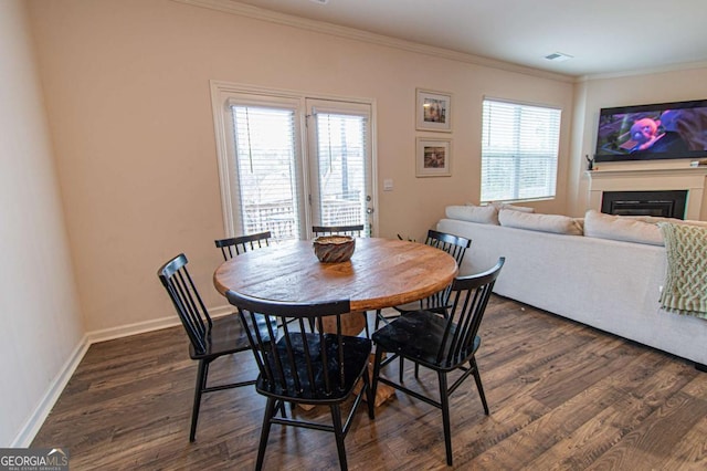 dining space featuring dark wood-style floors, ornamental molding, and baseboards