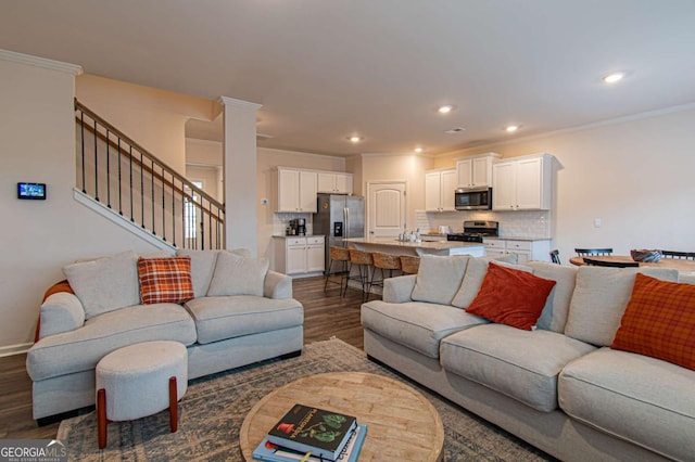 living room with dark wood-type flooring, recessed lighting, crown molding, and stairway