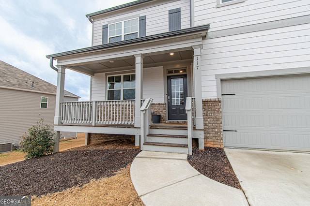 view of exterior entry featuring a garage, a porch, and brick siding