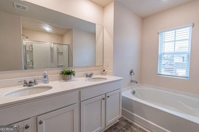 bathroom with a garden tub, double vanity, a stall shower, and a sink