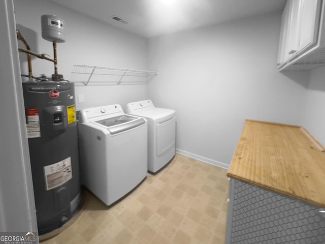 washroom featuring washer and clothes dryer, electric water heater, cabinet space, baseboards, and light floors