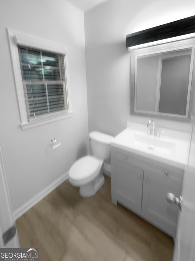 bathroom with vanity, toilet, wood finished floors, and baseboards