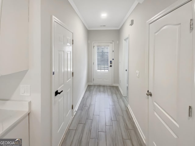 hallway with visible vents, baseboards, wood tiled floor, and crown molding