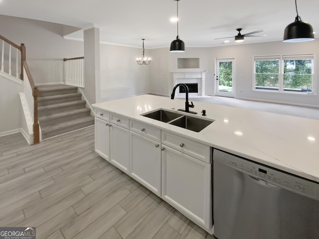 kitchen featuring ceiling fan, dishwasher, a fireplace, white cabinetry, and a sink