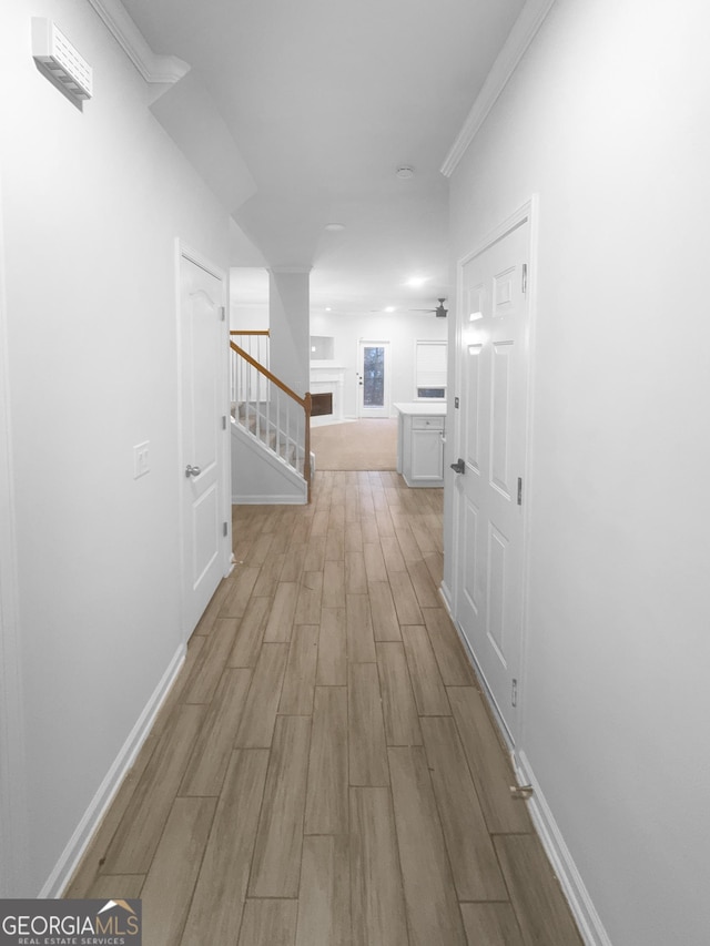 corridor with stairway, ornamental molding, baseboards, and wood finish floors