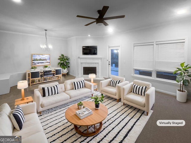 living room with ornamental molding, ceiling fan with notable chandelier, recessed lighting, a fireplace, and baseboards