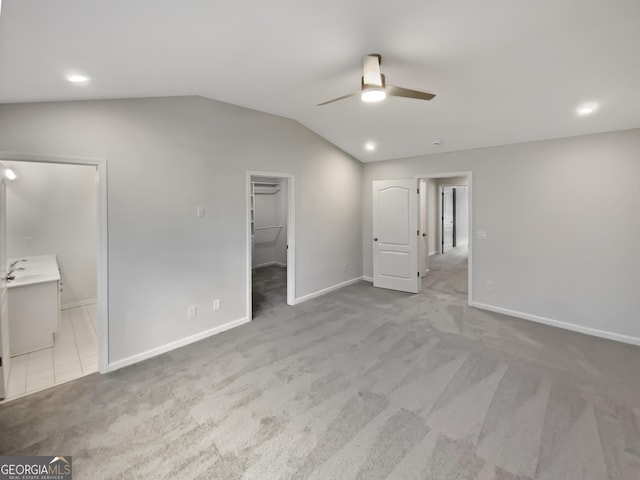 unfurnished bedroom featuring lofted ceiling, a spacious closet, carpet flooring, and a sink