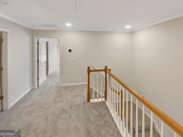 corridor with crown molding, baseboards, attic access, carpet floors, and an upstairs landing