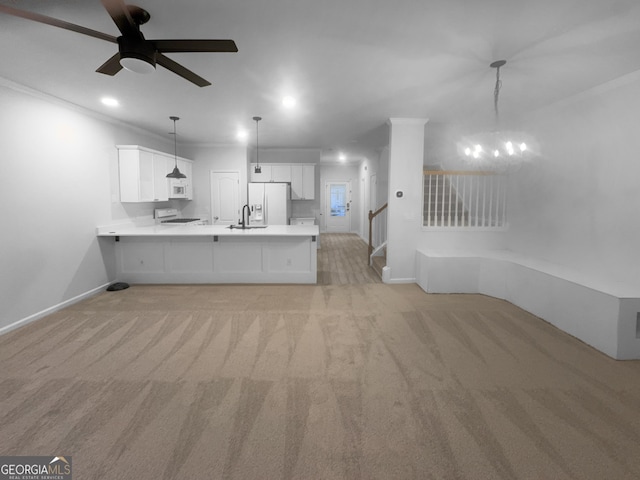 interior space with a peninsula, ornamental molding, light countertops, white cabinetry, and open floor plan