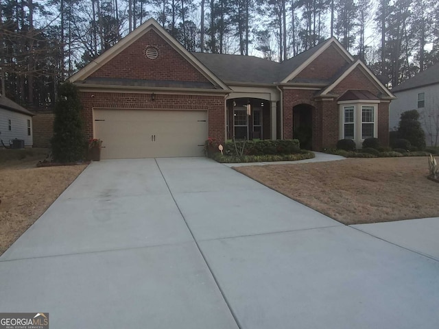 view of front of property featuring an attached garage, cooling unit, concrete driveway, and brick siding