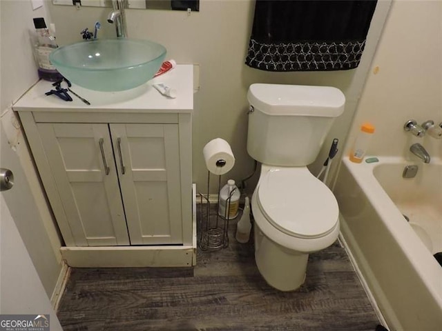 full bathroom featuring toilet, baseboards, wood finished floors, and vanity